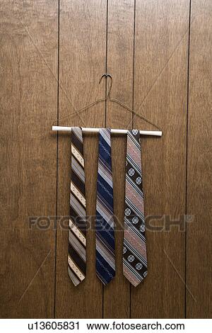 Stock Image - Three retro ties hanging on a wire hanger against wood paneling.. Fotosearch