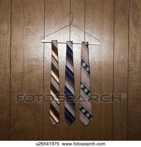 Stock Photography - Three retro ties hanging on a wire hanger against wood paneling. Fotosearch