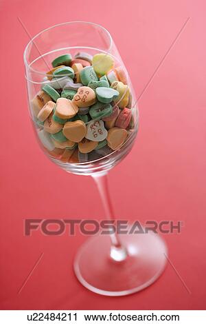 Wine glass full of colorful candy hearts with sayings on them on red background View Large Photo Image Stock Image - Wine glass full of colorful candy hearts with sayings on them on red background. Fotosearch