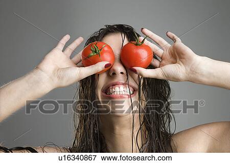 Stock Photo - Woman with tomatoes covering her eyes. Fotosearch