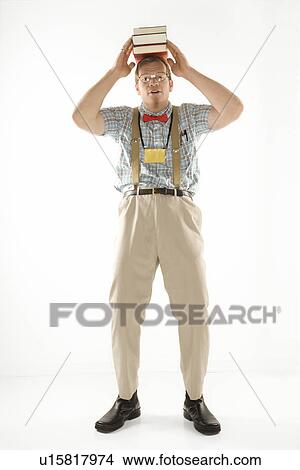 Picture - Young man dressed like nerd balancing books on head looking at viewer. Fotosearch