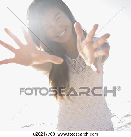 Stock Photo - Young woman with arms and hands stretched out toward viewer.. Fotosearch