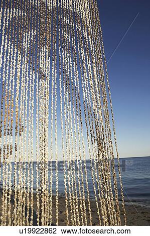Stock Image - Close-up of a beaded curtain on the beach. Fotosearch
