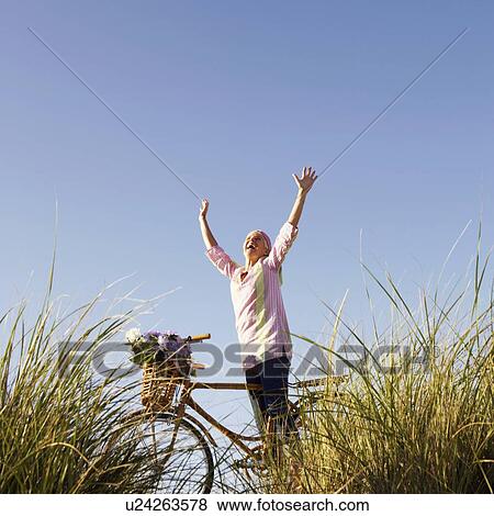 Low angle view of a mature woman standing with her arms raised View Large Photo Image Stock Photo - Low angle view of a mature woman standing with her arms raised. Fotosearch
