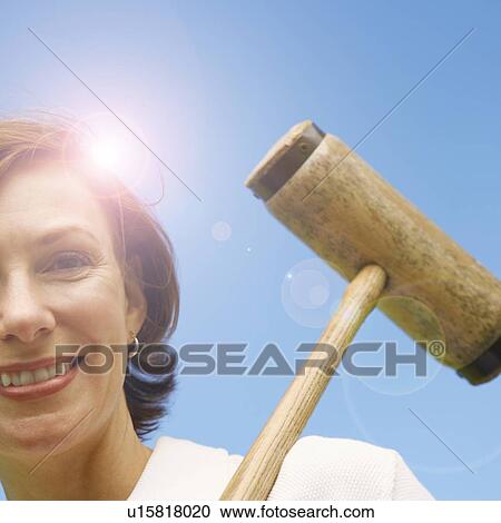 Low angle view of a mid adult woman holding a croquet mallet and smiling View Large Photo Image Stock Image - Low angle view of a mid adult woman holding a croquet mallet and smiling. Fotosearch