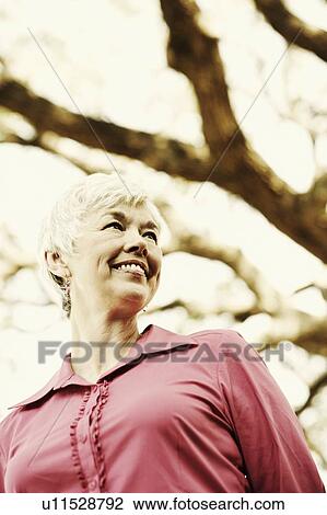 Stock Image - Low angle view of a senior woman smiling and looking sideways. Fotosearch