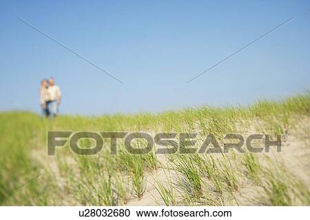 Stock Image - Mature couple standing on the beach. Fotosearch