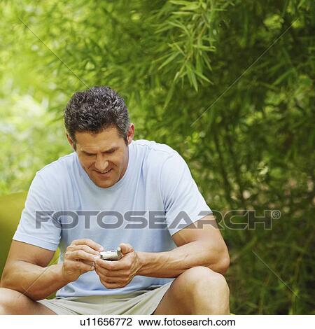 Mid adult man using a personal data assistant View Large Photo Image Stock Image - Mid adult man using a personal data assistant. Fotosearch