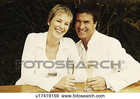 Stock Photo - Portrait of a mature couple holding champagne flutes and smiling. Fotosearch
