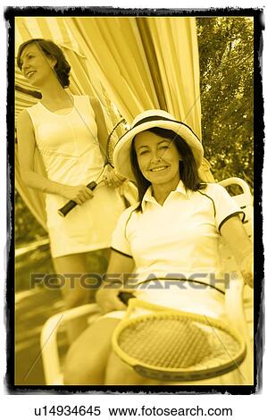 Portrait of a mature woman holding a tennis racket with a mid adult woman standing behind her View Large Photo Image Stock Photography - Portrait of a mature woman holding a tennis racket with a mid adult woman standing behind her. Fotosearch