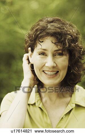 Stock Image - Portrait of a mature woman with her hand in her hair. Fotosearch