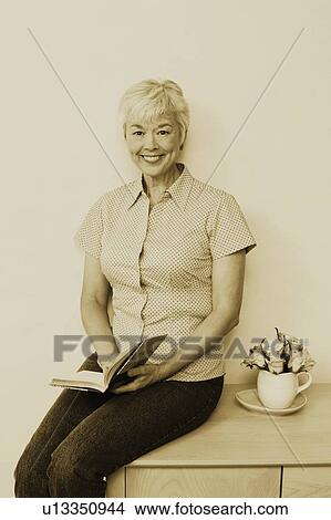 Portrait of a senior woman holding a book and smiling View Large Photo Image Picture - Portrait of a senior woman holding a book and smiling. Fotosearch