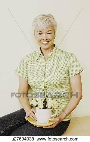 Portrait of a senior woman holding a coffee cup and smiling View Large Photo Image Stock Photo - Portrait of a senior woman holding a coffee cup and smiling. Fotosearch
