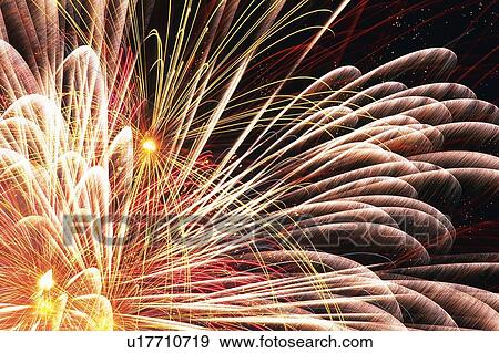 Stock Photo -  Light Red and Purple-colored Fireworks Exploding in the Night Sky, Long Exposure, Low Angle View. Fotosearch