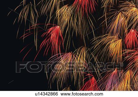 Stock Photograph -  Multicolored Fireworks Exploding in the Night Sky, Long Exposure, Low Angle View . Fotosearch