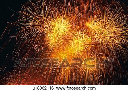 Stock Photograph -  Orange and Gold-colored Fireworks Exploding in the Night Sky, Long Exposure, Low Angle View. Fotosearch