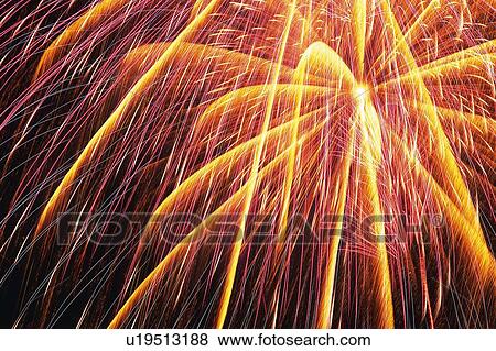 Stock Photo -  Orange and Pink-colored Fireworks Exploding in the Night Sky, Long Exposure, Low Angle View. Fotosearch