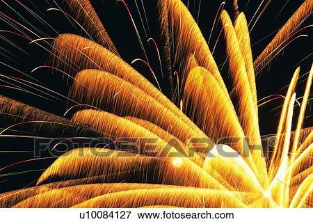 Stock Photo -  Orange-colored Fireworks Exploding in the Night Sky, Long Exposure, Low Angle View. Fotosearch