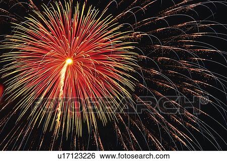Stock Photograph -  Red and Gold-colored Fireworks Exploding in the Night Sky, Low Angle View, Long Exposure. Fotosearch
