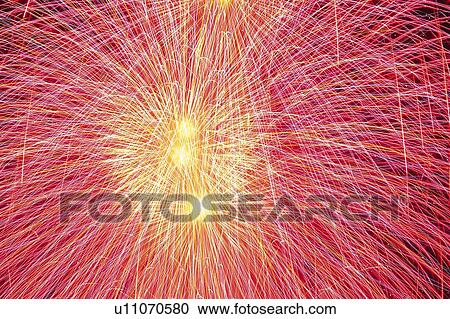 Stock Image -  Red and Pink-colored Fireworks Exploding in the Night Sky, Low Angle View, Long Exposure. Fotosearch