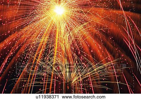 Stock Image -  Red, Orange and Yellow-colored Fireworks Exploding in the Night Sky, Long Exposure, Low Angle View . Fotosearch