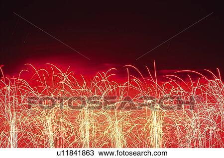 Stock Image -  Several Little Red and Yellow-colored Fireworks Exploding in the Night Sky, Long Exposure, Front View. Fotosearch