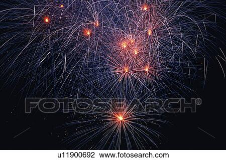 Stock Image -  Small Red-colored Fireworks Exploding in the Night Sky, Long Exposure, Low Angle View . Fotosearch