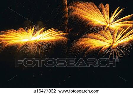 Stock Image -  Three Orange and Yellow-colored Fireworks Exploding in the Night Sky, Long Exposure, Front View . Fotosearch