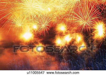 Stock Photo -  Yellow and Orange-colored Fireworks Exploding in the Night Sky, Long Exposure, Low Angle View . Fotosearch