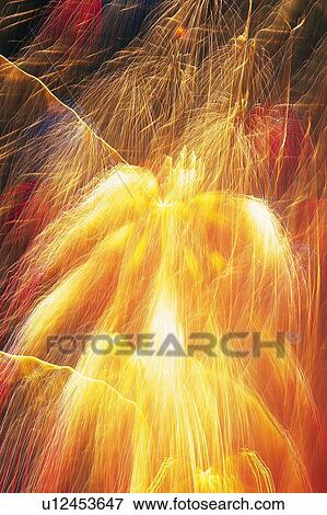 Stock Photo -  Yellow and Red-colored Fireworks Exploding in the Night Sky, Long Exposure, Low Angle View. Fotosearch