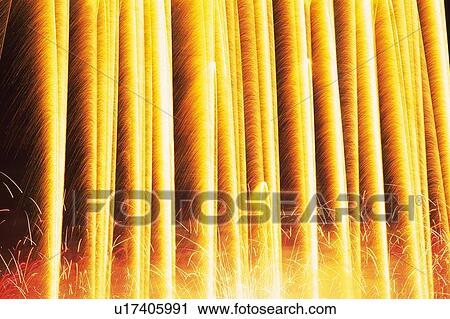 Stock Image -  Yellow-colored Lined Up Fireworks Exploding in the Night Sky, Long Exposure. Fotosearch