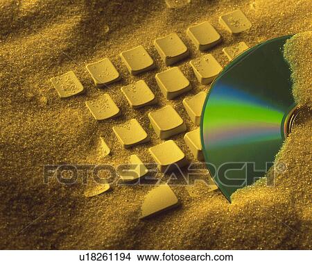 Picture - Computer Keyboard and CD-R buried in sand, Close Up, High Angle View. Fotosearch