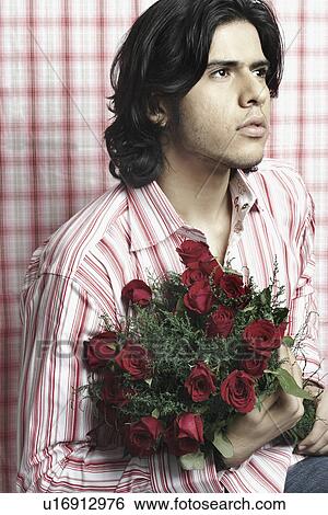 Stock Photograph - Close-up of a young man holding a bouquet of flowers. Fotosearch