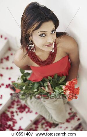 Stock Photo - High angle view of a young woman holding a bouquet of flowers. Fotosearch