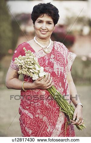 Stock Image - Portrait of a mature woman holding a bunch of flowers. Fotosearch