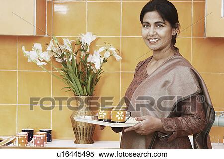 Stock Photography - Portrait of a mature woman holding a tray with two cups. Fotosearch