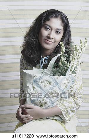 Stock Image - Portrait of a young woman holding a bag of flowers. Fotosearch
