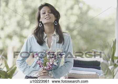 Portrait of a young woman holding a bunch of flowers View Large Photo Image Stock Image - Portrait of a young woman holding a bunch of flowers. Fotosearch