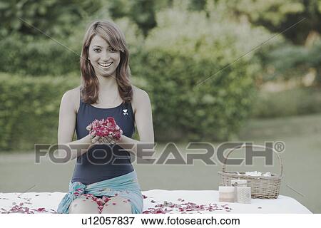 Stock Photo - Portrait of a young woman holding rose petals in her palm. Fotosearch