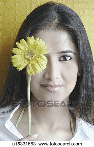 Portrait of a young woman with a flower in front of her face View Large Photo Image Stock Image - Portrait of a young woman with a flower in front of her face. Fotosearch