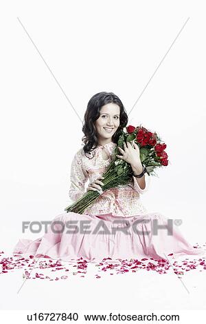 Stock Image - Portrait of a young woman with a bouquet of flowers smiling. Fotosearch