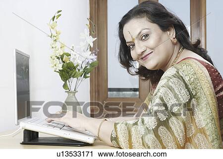 Side profile of a mature woman sitting in front of a laptop View Large Photo Image Stock Image - Side profile of a mature woman sitting in front of a laptop. Fotosearch