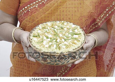 Stock Image - Mid section view of a woman holding a bowl of rice. Fotosearch