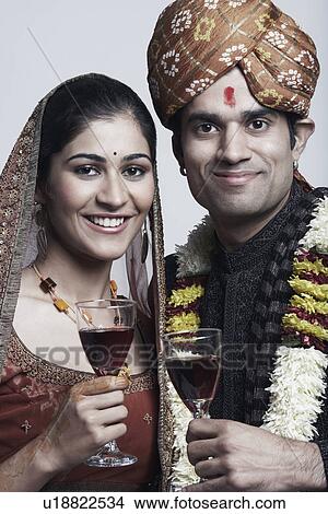 Portrait of a newlywed couple holding glasses of red wine View Large Photo Image Picture - Portrait of a newlywed couple holding glasses of red wine. Fotosearch