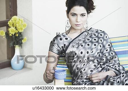 Stock Image - Portrait of a young woman holding a cup of tea. Fotosearch