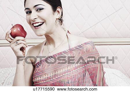 Stock Image - Portrait of a young woman holding an apple. Fotosearch