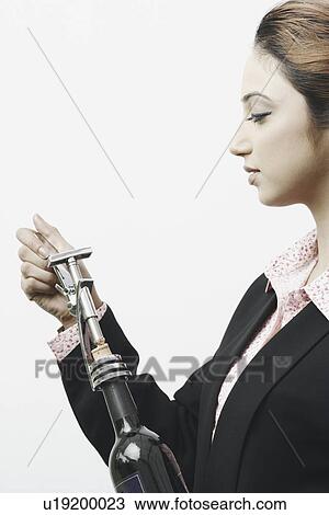 Side profile of a businesswoman opening a champagne bottle View Large Photo Image Stock Image - Side profile of a businesswoman opening a champagne bottle. Fotosearch