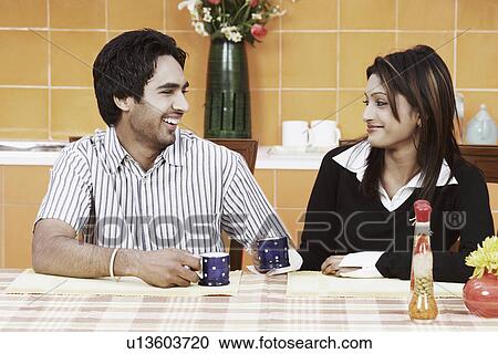 Stock Image - Young couple having tea at the dining table. Fotosearch