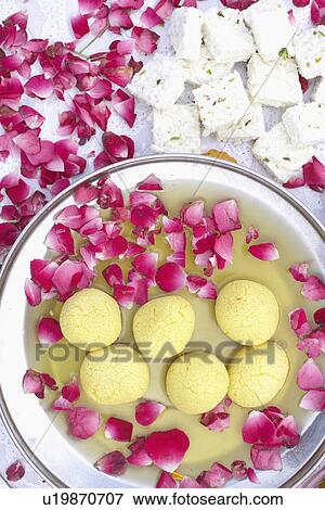 Stock Photo - High angle view of a dish of Indian sweets with flower petals around it. Fotosearch