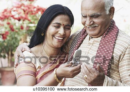 Stock Image - Close-up of a mature couple looking at a mobile phone. Fotosearch